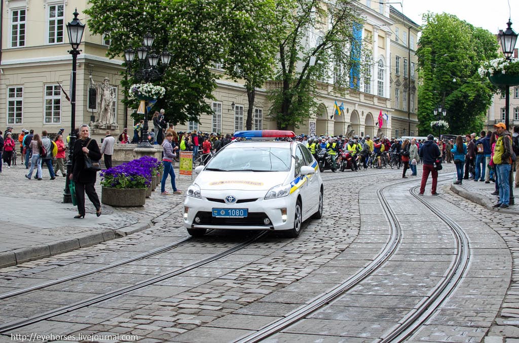 Група людей, які йдуть вниз по тротуару поруч з автомобілем