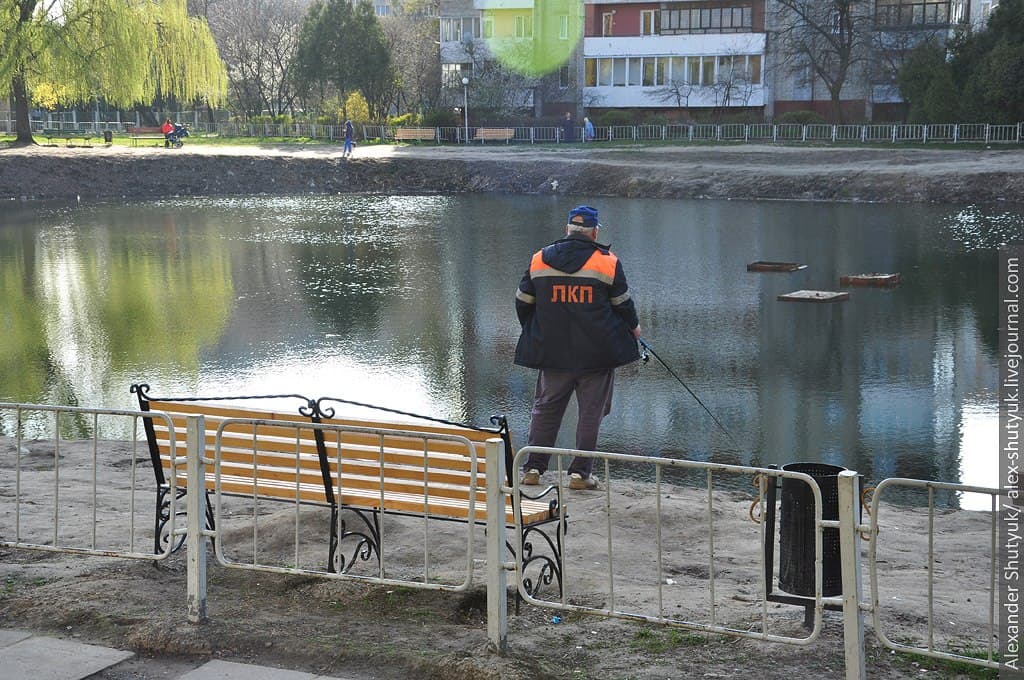 Людина сидить на лавці поруч з водоймою