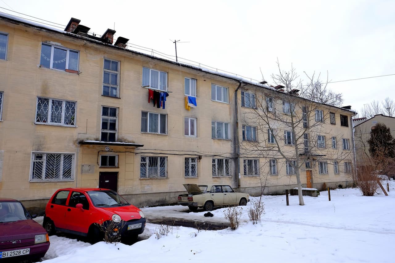 Автомобіль, припаркований перед будинком, вкрите снігом