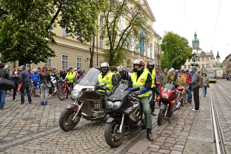 Група людей на тротуарі поруч з мотоциклом